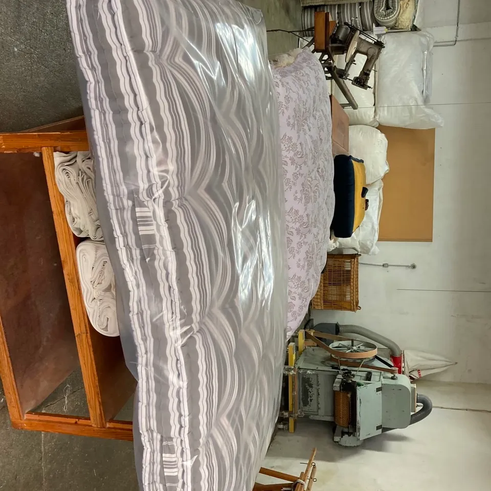 Atelier de matelassier : machine à carder au fond, matelas de laine sur tréteaux
