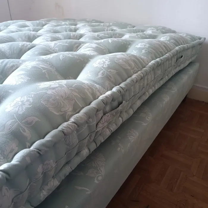 Matelas capitonné vert d’eau posé sur son sommier assorti, sur parquet