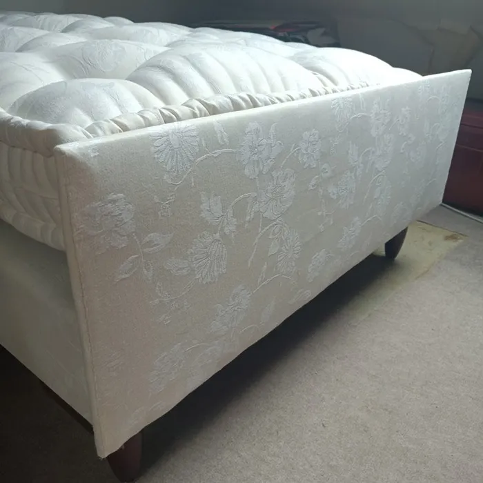 Ensemble matelas et sommier en damassé blanc reposant sur ses pieds de bois tournés