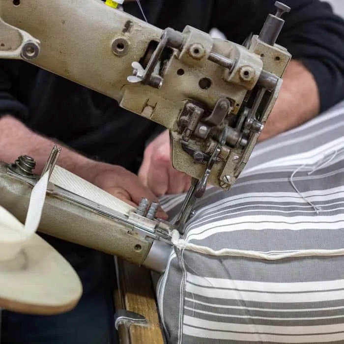 Machine à piquer d'atelier guidée à la main sur le bord d'un matelas rayé