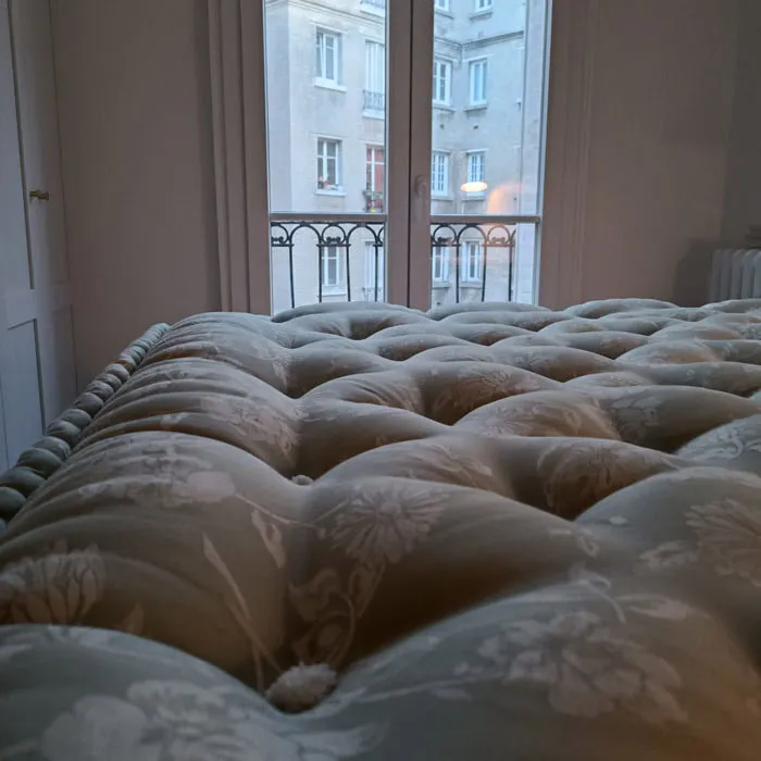 Matelas en laine capitonné posé bien à plat devant une fenêtre parisienne