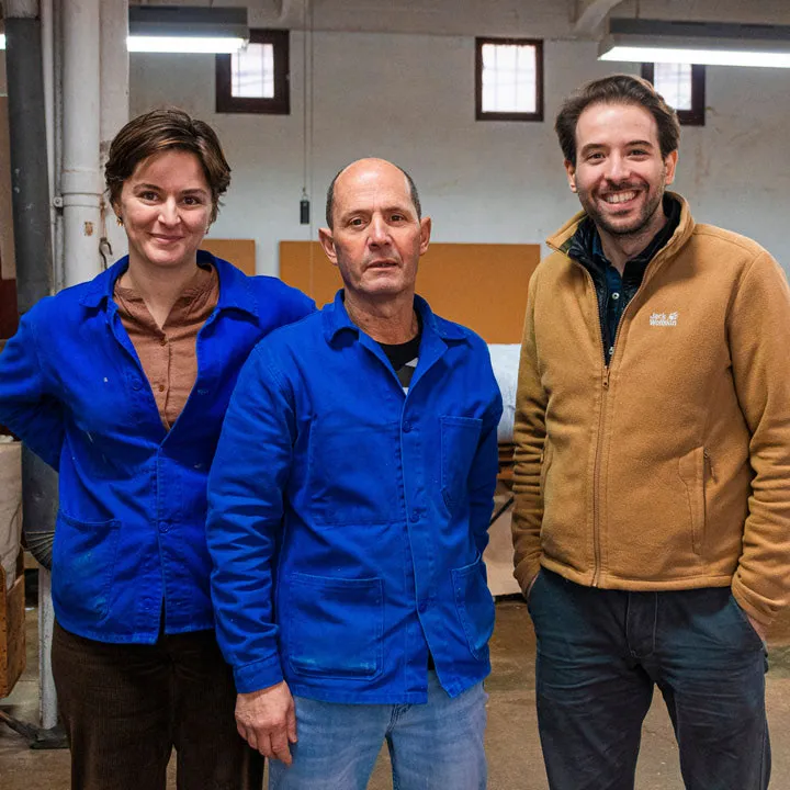 Les trois matelassiers de l'atelier Le Briand, en tenue de travail, dans leur atelier parisien
